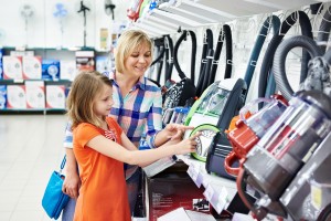 Mother and daughter shopping for electric vacuum cleaner, smiling