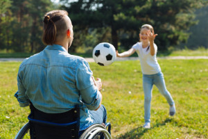 84156276 - incapacitated young man catching ball thrown by daughter